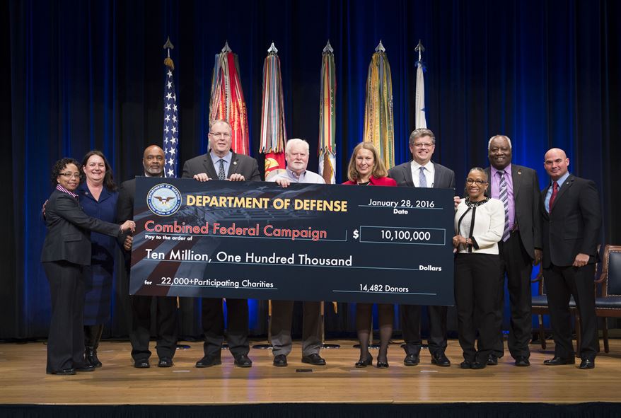 Deputy Defense Secretary Bob Work, fourth from left, presents a representation of a check of donated funds