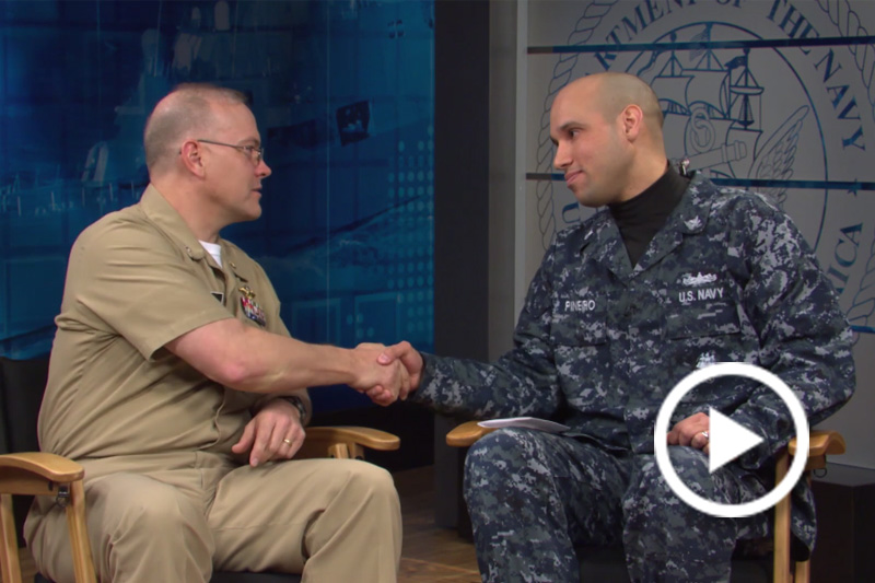 Screen grab of Petty Officer 2nd Class Dominique A. Pineiro and Cmdr. John Biery shaking hands.