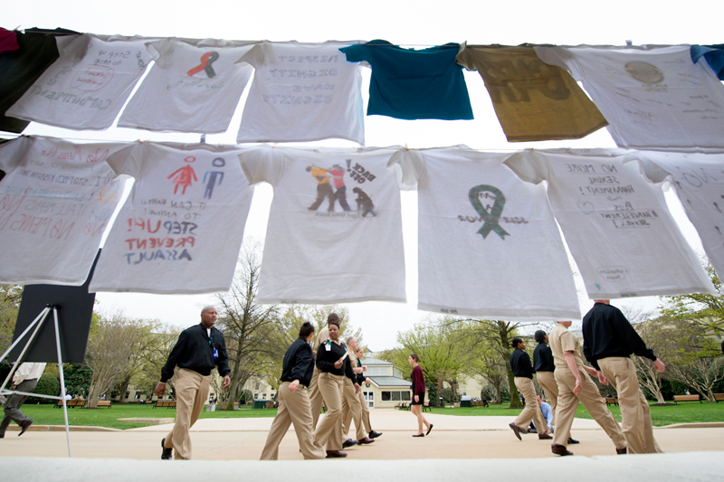 Navy officers walk by a display of T-shirts decorated to support survivors of sexual assault