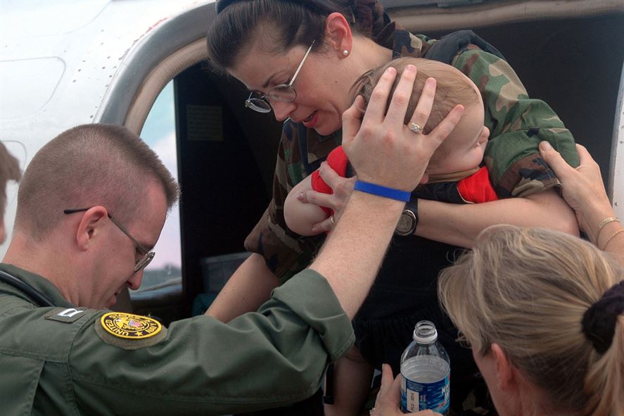 Navy Lt. Larry Anderson helps Air Force Col. Norma Allgood and her 15-month-old son out of an aircraft.