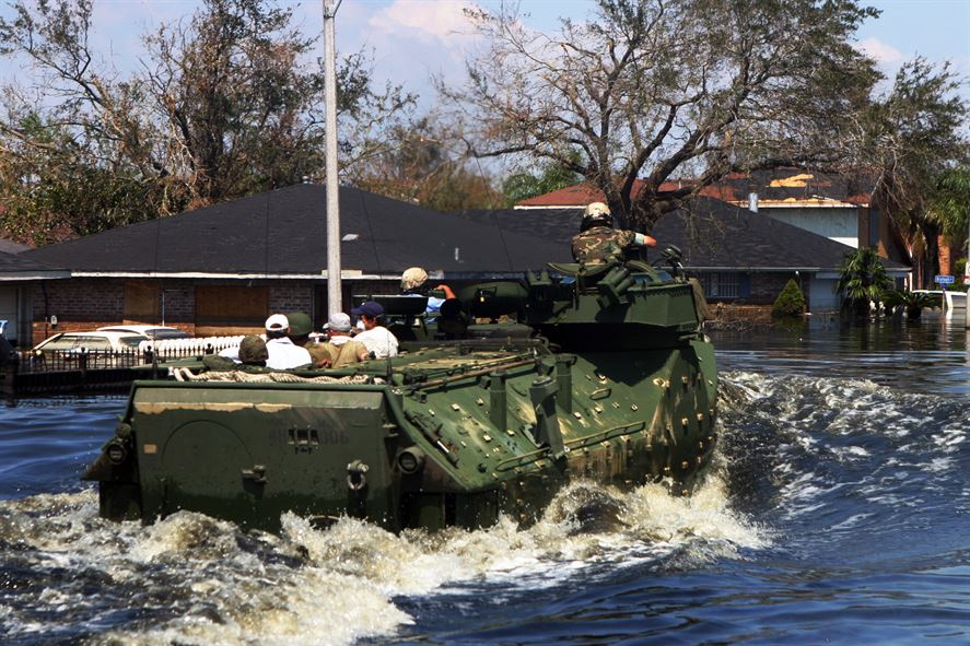 Marines in amphibious vehicles and infantrymen travel down the decimated streets of Orleans Parish conducting search-and-rescue operations 