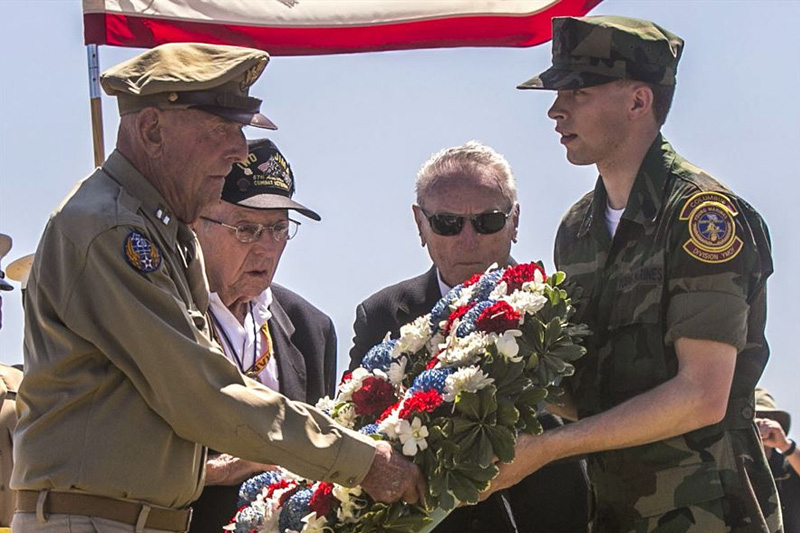 Photo of Former Army Air Corps Capt. Jerry Yellin, left, Navy Seabee Jack Lazere, center left, and Marine Carl DeHaven, veterans of the Battle of Iwo Jima, accepting a wreath from a member of the Young Marines group.