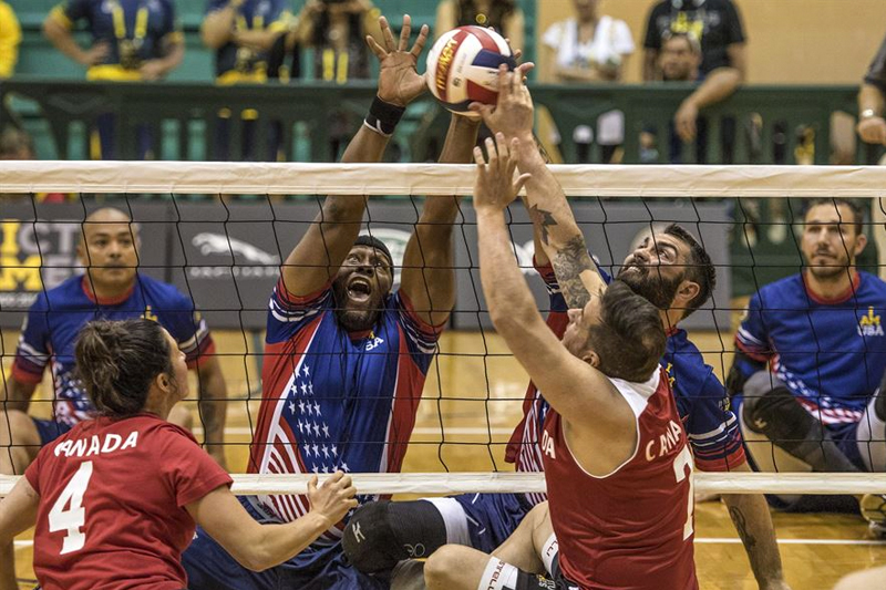 Army veteran Alexander Shaw, left center, and Air Force veteran Nicholas Dadgostar, right center, attempt to block the ball against the Canadian team playing a sitting volleyball competition