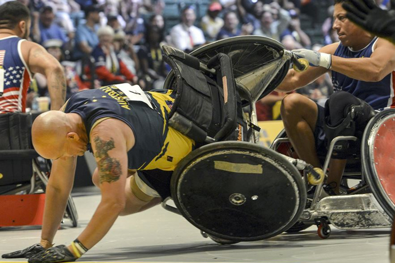 Australia’s Trent Serafini, left, flips in his wheel chair as a U.S. team member attempts to keep him upright during their semi-final wheelchair rugby match 