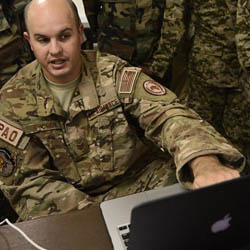 A service member gestures toward laptop.