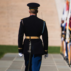 A service member stands at attention.