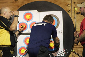 Navy athlete crouching in front of archery target.