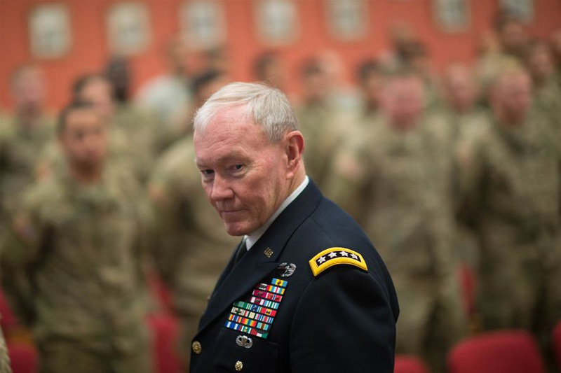 U.S. Army Gen. Martin E. Dempsey, chairman of the Joint Chiefs of Staff, gazing toward the camera with service men and women in the background.
