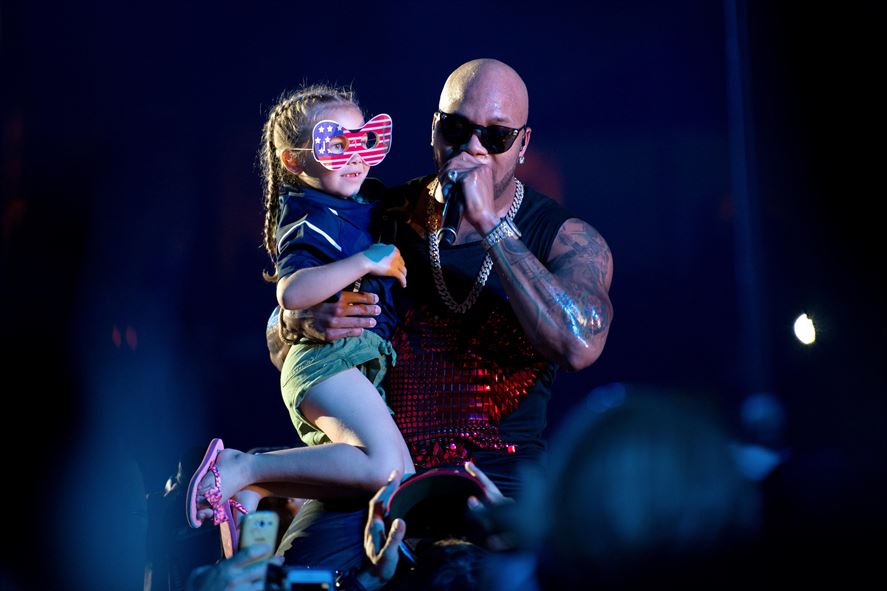 Hip-hop artist Flo Rida holds the 7-year-old daughter of U.S. team member Marine Corps Staff Sgt. Rafael Cervantes while performing