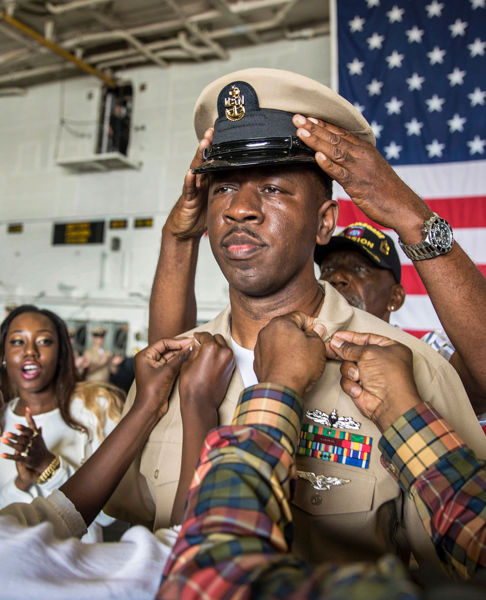 A sailor's family members participate in a ceremony promoting him to the rank of senior chief petty officer.