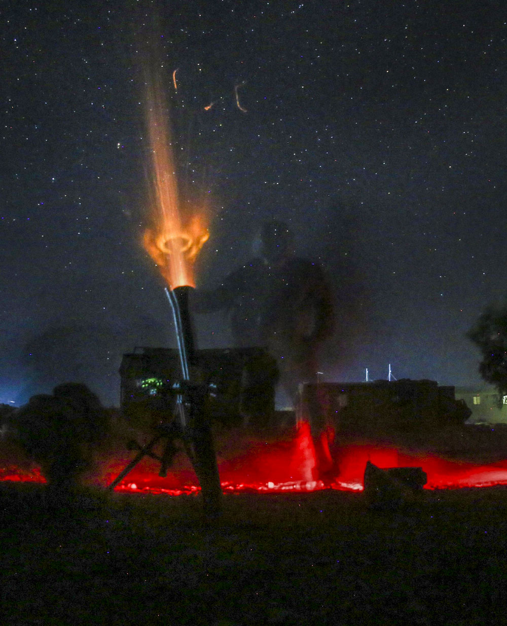 Marines fire a nonexplosive illumination round at night from an 81 mm mortar to deter enemy activity.